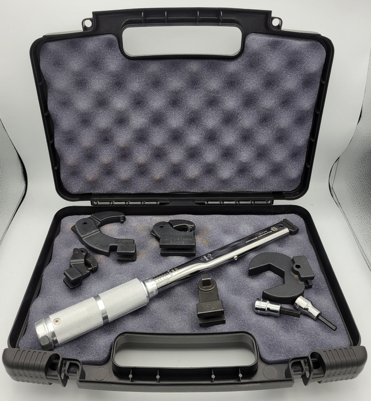 Torque wrench kit with various tools in an open black case on a white background