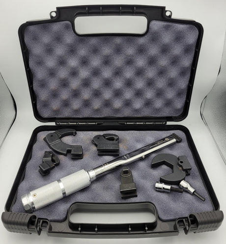Torque wrench kit with various tools in an open black case on a white background